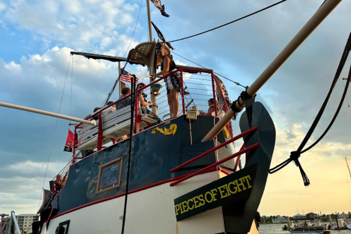 Pirate ship 'Pieces of Eight' docked with people on deck, cloudy sky background.