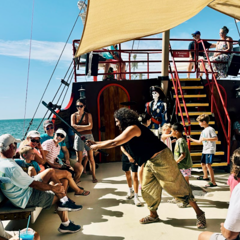 People enjoying a pirate-themed activity on a boat under a sunny sky.