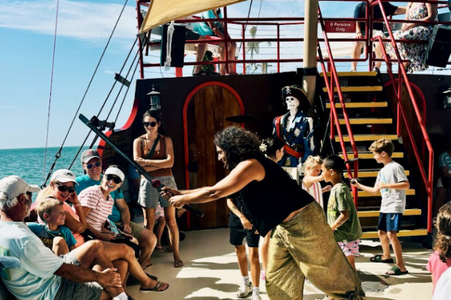 People enjoying a pirate-themed activity on a boat under a sunny sky.