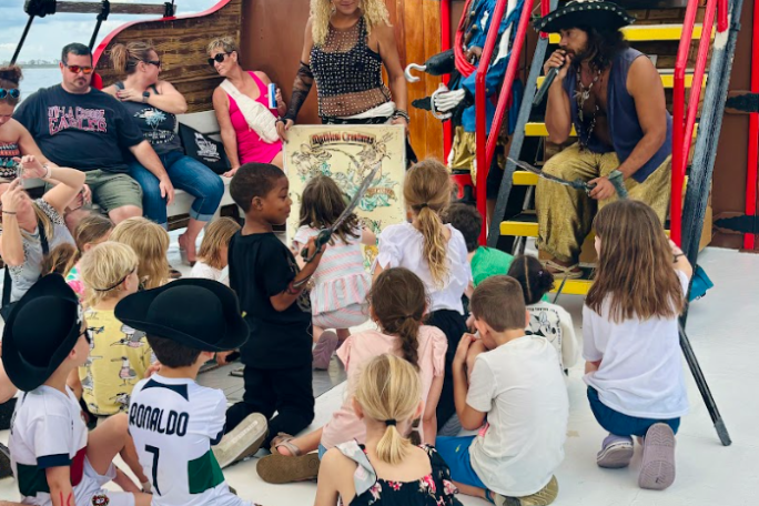 Pirates entertaining children on a ship with costumes and a treasure map.