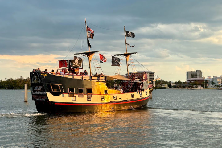 A pirate-themed tour boat on a river, with cityscape in the background.