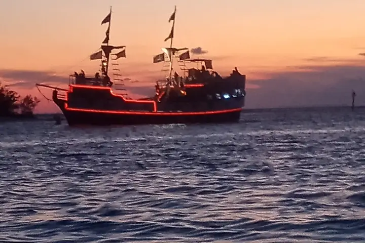 Sailing ship with red lights at sunset on the ocean.