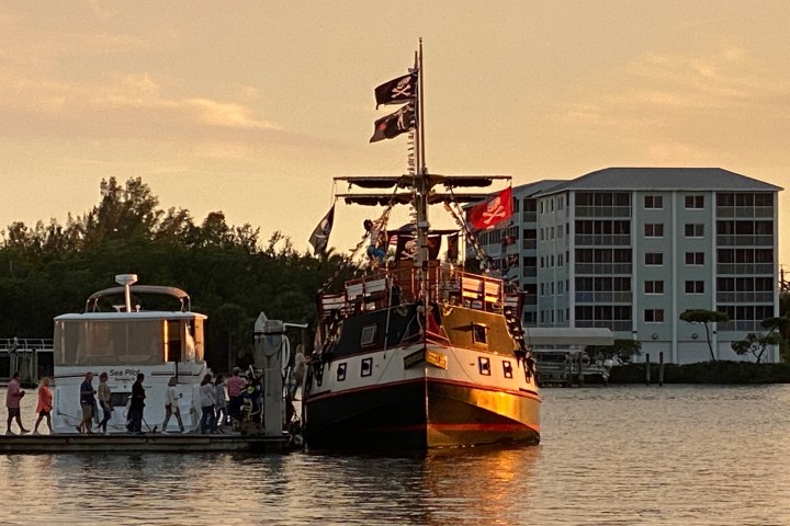Pirate-themed ship docked at sunset with people walking on pier.