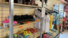 Gift shop with plush toys, clothing, pirate flags, and colorful souvenirs on display shelves.