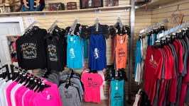 Colorful t-shirts and tank tops displayed on racks in a shop.