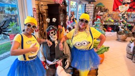 Two people in Minion costumes pose with a pirate skeleton in a colorful novelty shop.