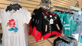 Children's clothing on display, including mermaid dress, pirate jacket, and colorful hoodies.