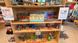 Gift shop display with nautical-themed items and name charts on a wooden shelf.