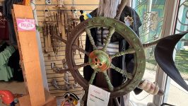Pirate mannequin steering wheel display with decor items and plush toys in store.