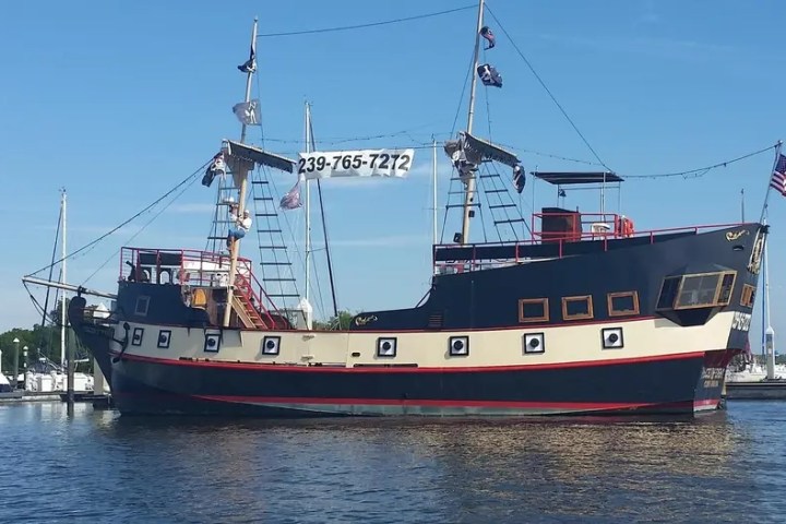 Large pirate ship docked with a phone number banner across the sails.