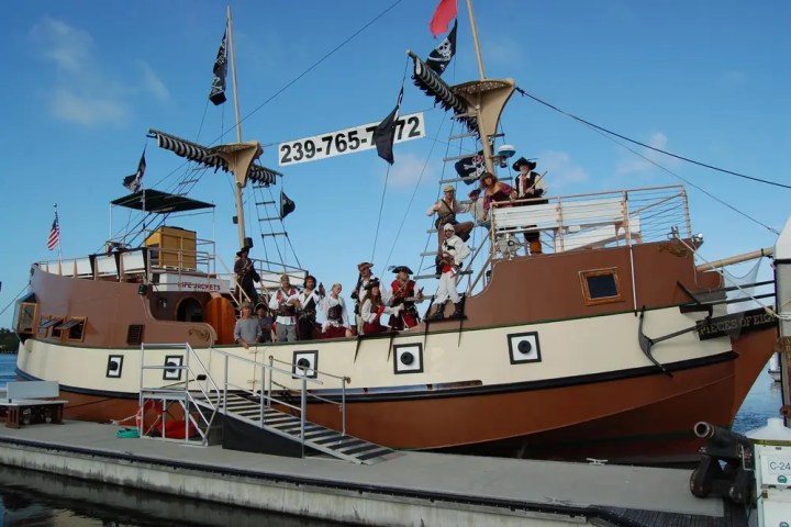 Pirate-themed ship docked with people in costumes on board.