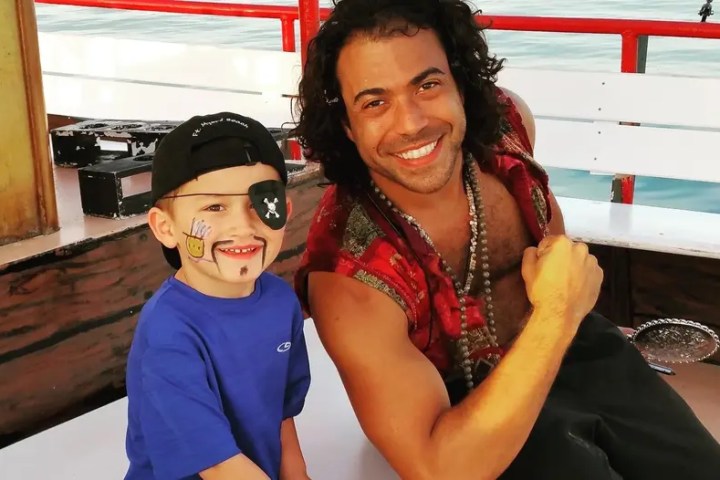 Smiling man and young boy with face paint on a boat.